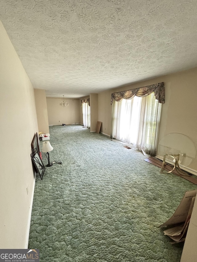 unfurnished room with carpet flooring, a textured ceiling, and a chandelier