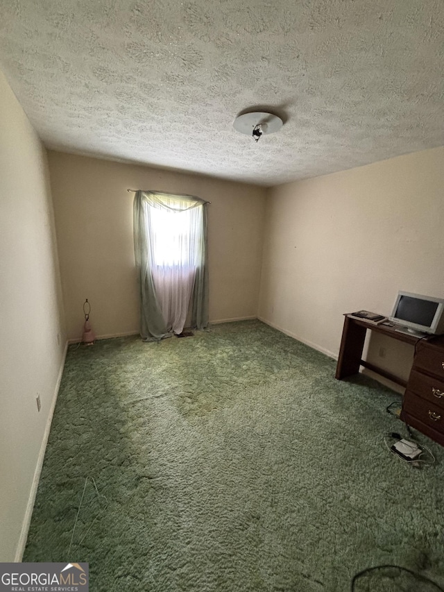 carpeted spare room with a textured ceiling and baseboards