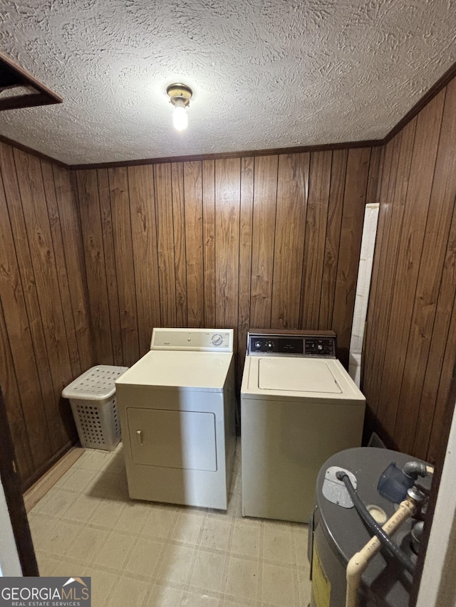 laundry area with light floors, washing machine and clothes dryer, wood walls, and a textured ceiling