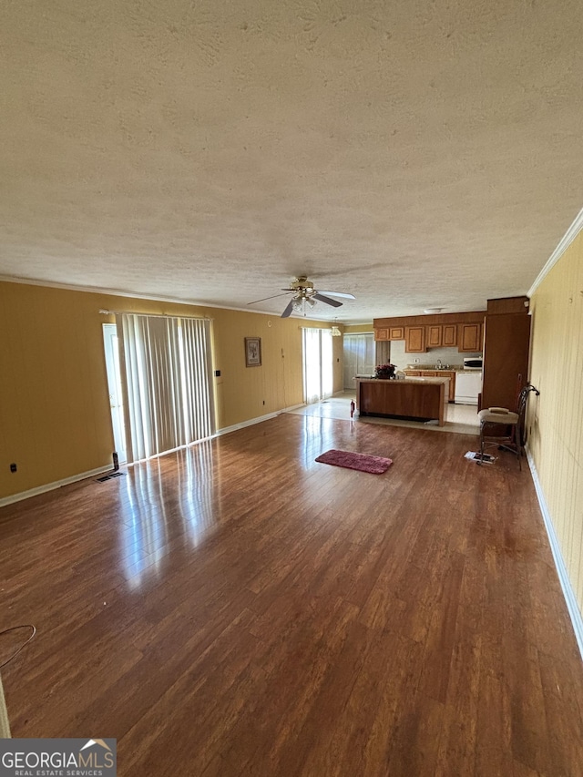 unfurnished living room featuring a textured ceiling, dark wood-style flooring, ceiling fan, and baseboards