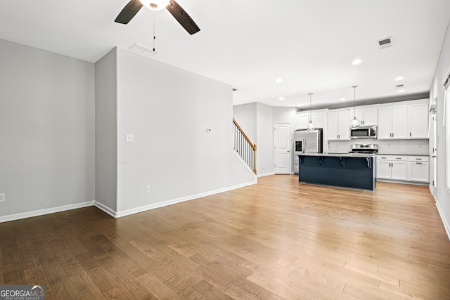 126 Ashton Pl, Newnan, GA 30265 - unfurnished living room with visible vents, recessed lighting, stairway, light wood finished floors, and a ceiling fan