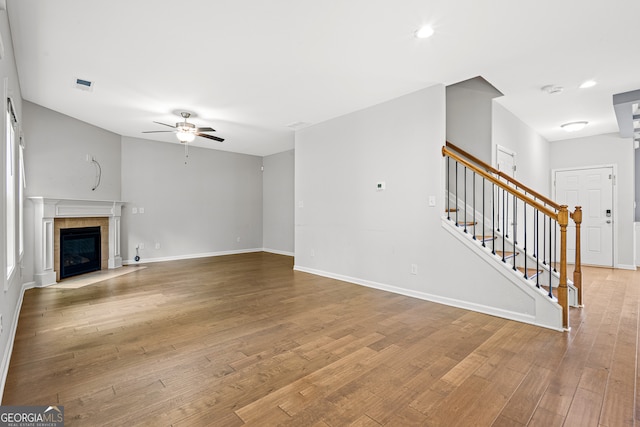 126 Ashton Pl, Newnan, GA 30265 - unfurnished living room with a tile fireplace, baseboards, ceiling fan, wood finished floors, and stairway