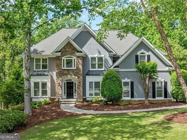 craftsman house with stucco siding, a standing seam roof, stone siding, and a front lawn