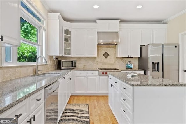 kitchen with stainless steel appliances, a sink, crown molding, white cabinets, and glass insert cabinets