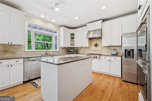 kitchen featuring stainless steel appliances, under cabinet range hood, white cabinetry, a sink, and recessed lighting