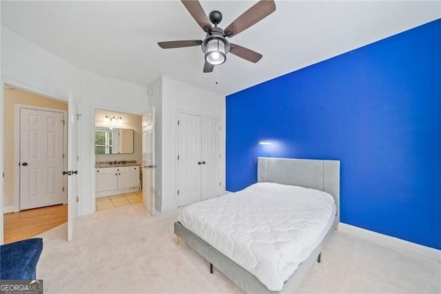 bedroom featuring light colored carpet, ceiling fan, a closet, and ensuite bath