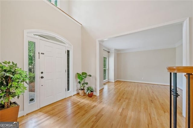 entryway with healthy amount of natural light, wood finished floors, baseboards, and crown molding