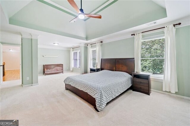 carpeted bedroom with a raised ceiling, baseboards, and ceiling fan