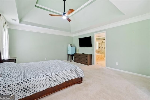 carpeted bedroom featuring a tray ceiling, ornamental molding, baseboards, connected bathroom, and ceiling fan