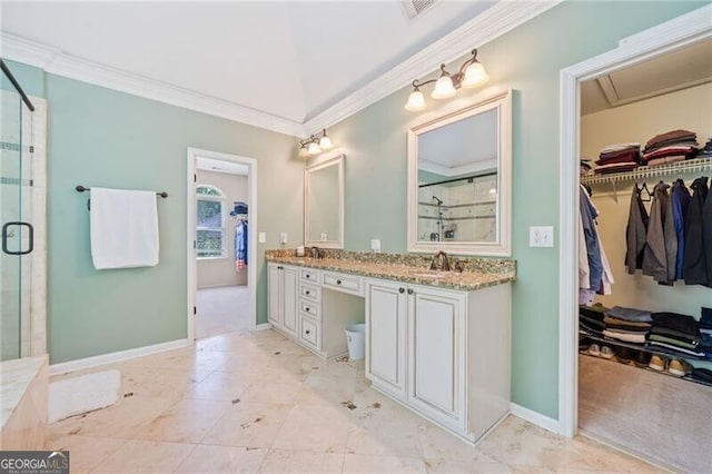 bathroom featuring a shower stall, ornamental molding, a walk in closet, double vanity, and baseboards