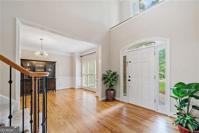 foyer entrance featuring stairway, a chandelier, wood finished floors, and crown molding