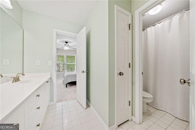 bathroom with vanity, toilet, tile patterned flooring, baseboards, and ceiling fan