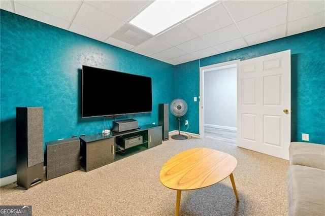 living area featuring a drop ceiling and carpet floors