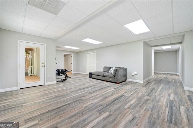 unfurnished room featuring wood finished floors, a drop ceiling, and baseboards