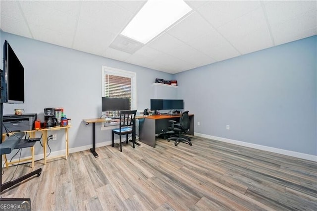 office area with wood finished floors, a drop ceiling, and baseboards
