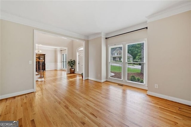 unfurnished living room featuring ornamental molding, light wood-type flooring, a chandelier, and baseboards