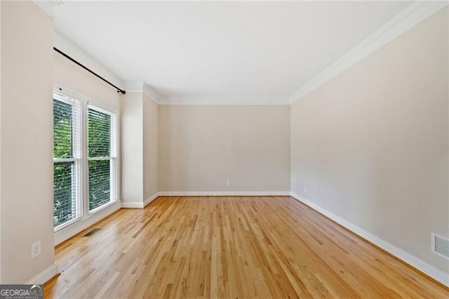 unfurnished room with wood finished floors, crown molding, and baseboards