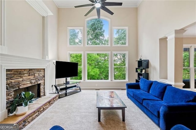 living area featuring a ceiling fan, a high ceiling, ornamental molding, a fireplace, and carpet floors