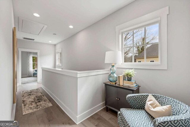hall with attic access, visible vents, plenty of natural light, and wood finished floors
