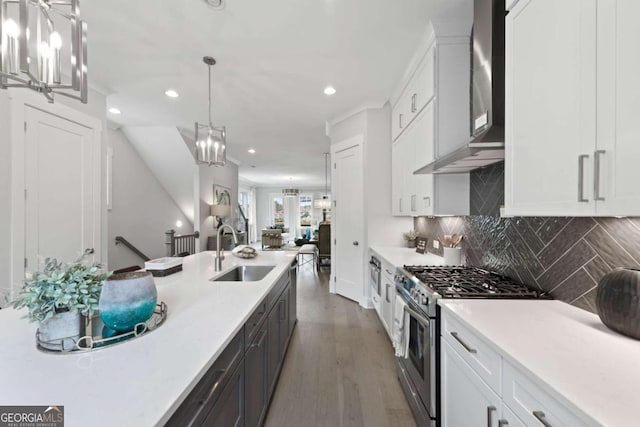 kitchen with white cabinets, wall chimney exhaust hood, stainless steel range with gas stovetop, and a sink
