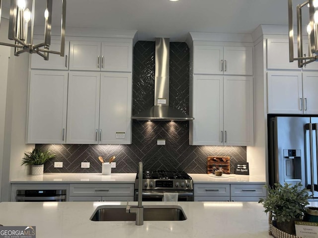 kitchen featuring backsplash, white cabinets, appliances with stainless steel finishes, and wall chimney exhaust hood