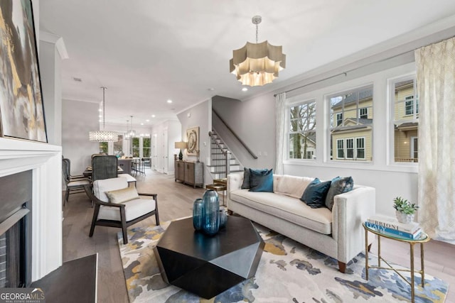 living area with wood finished floors, a chandelier, a fireplace, and stairs