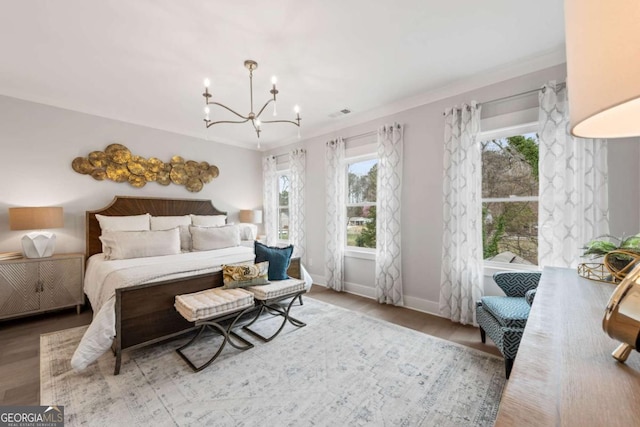 bedroom featuring visible vents, wood finished floors, baseboards, and a notable chandelier