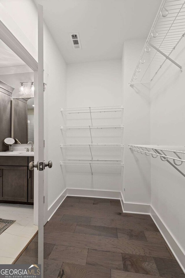 walk in closet with a sink, visible vents, and wood finished floors