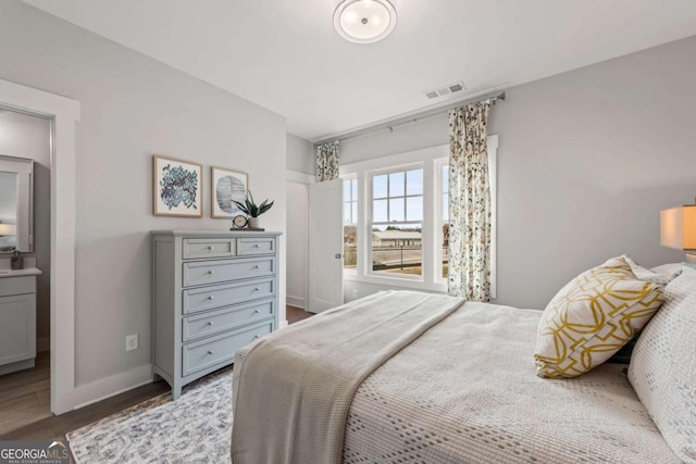 bedroom with visible vents, wood finished floors, and baseboards