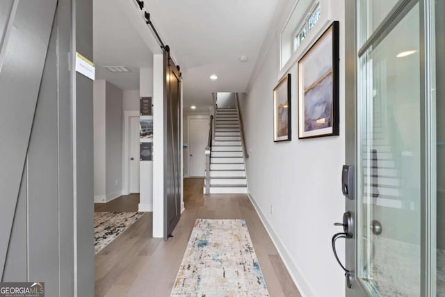 foyer with baseboards, recessed lighting, a barn door, and wood finished floors