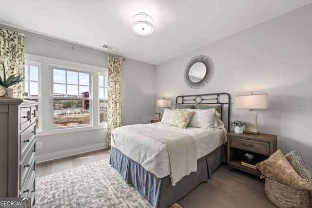 bedroom featuring baseboards, visible vents, and wood finished floors