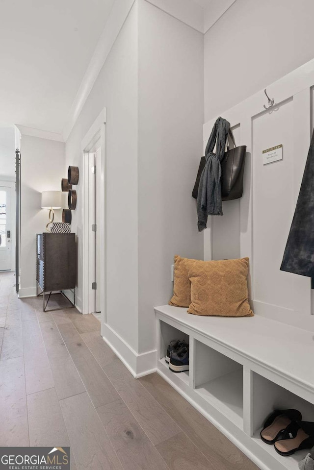 mudroom with ornamental molding, baseboards, and wood finished floors