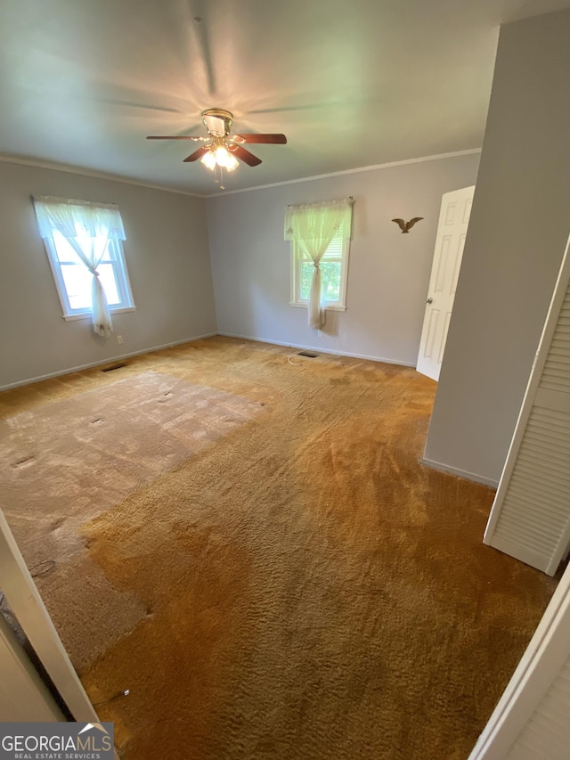 unfurnished room with ornamental molding, carpet floors, ceiling fan, and baseboards