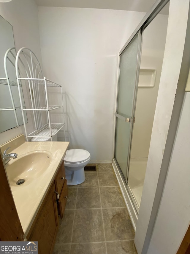 full bathroom with a stall shower, vanity, toilet, baseboards, and tile patterned flooring