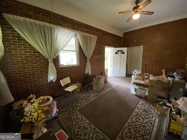 living area featuring brick wall and ceiling fan
