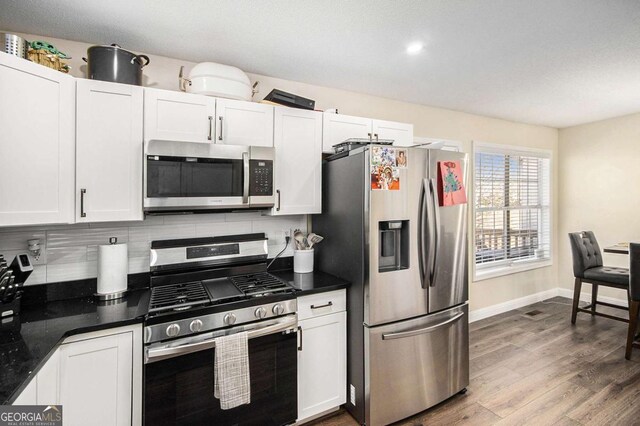 7760 Poppy Dr, Winston, GA 30187 - kitchen featuring white cabinetry, dark countertops, appliances with stainless steel finishes, and decorative backsplash