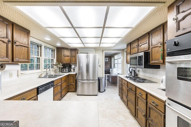 kitchen with a sink, a wealth of natural light, decorative backsplash, and appliances with stainless steel finishes