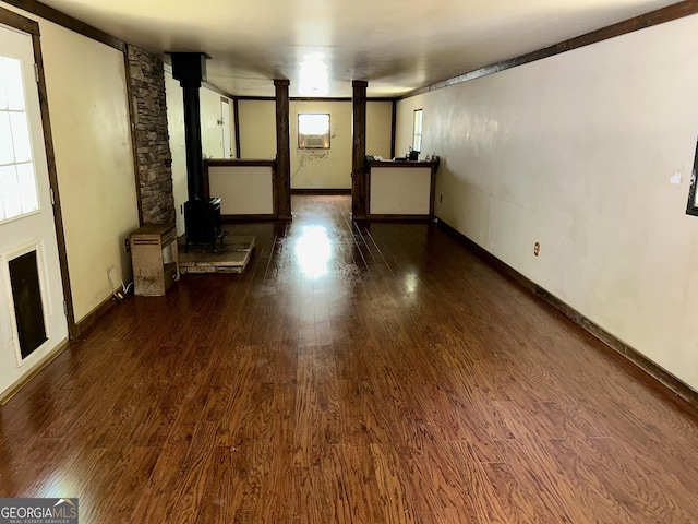 unfurnished living room featuring a wood stove, baseboards, and wood finished floors