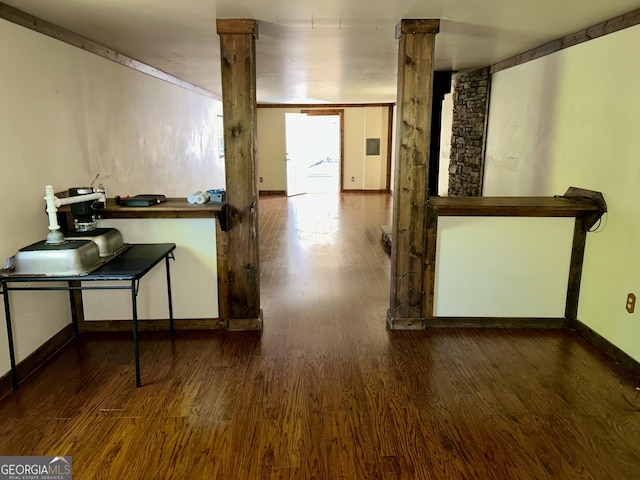 hallway featuring decorative columns, baseboards, and wood finished floors