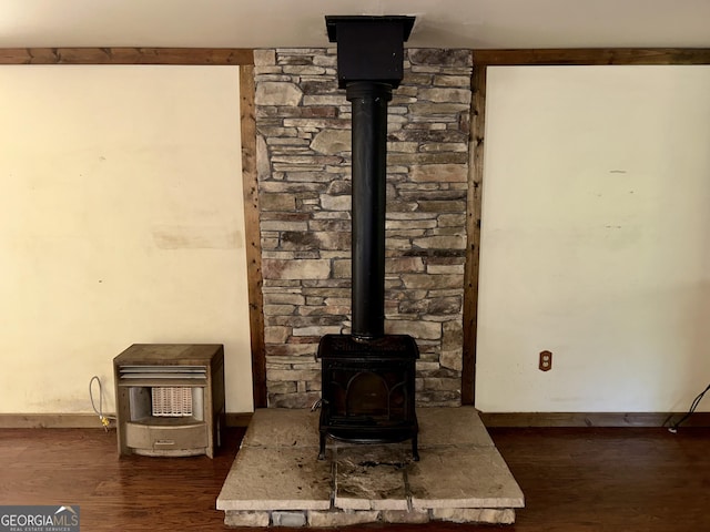 interior details with a wood stove, baseboards, and wood finished floors