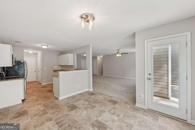 kitchen with ceiling fan, white cabinetry, open floor plan, decorative backsplash, and baseboards
