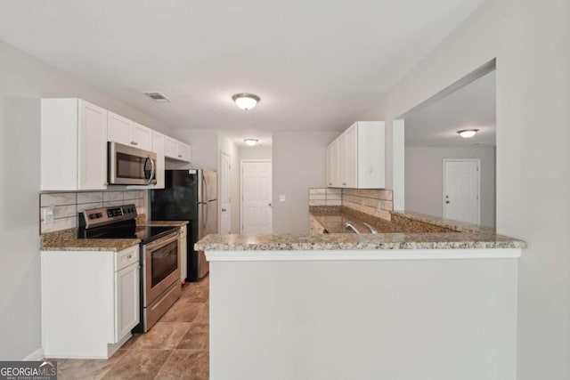 kitchen featuring light stone counters, stainless steel appliances, tasteful backsplash, and visible vents
