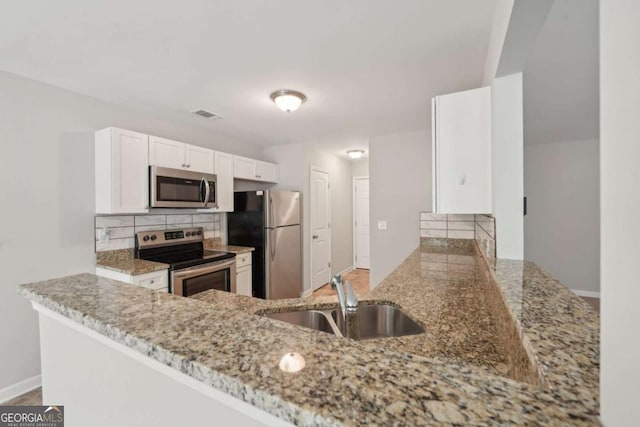kitchen with a sink, stainless steel appliances, white cabinetry, visible vents, and tasteful backsplash