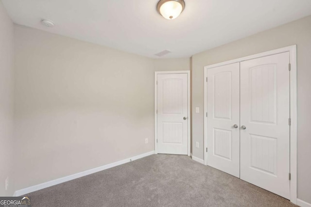 unfurnished bedroom featuring a closet, baseboards, and carpet floors