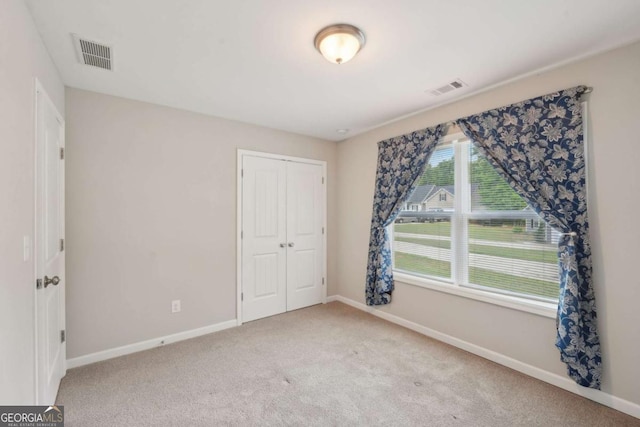 unfurnished bedroom featuring baseboards, visible vents, and carpet