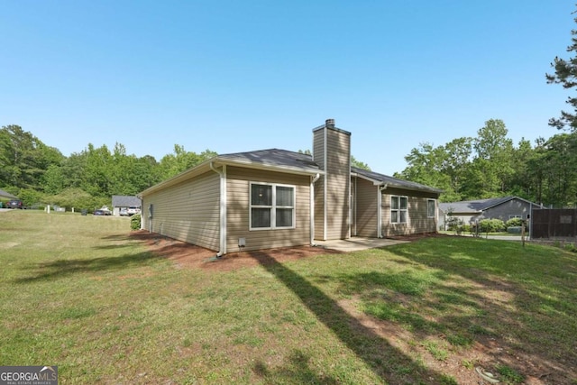 rear view of house featuring a yard and a chimney