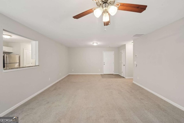 empty room with baseboards, a ceiling fan, and light colored carpet
