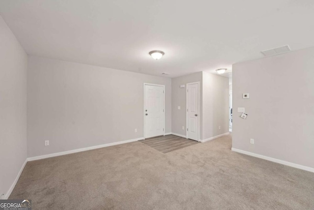carpeted spare room featuring visible vents and baseboards