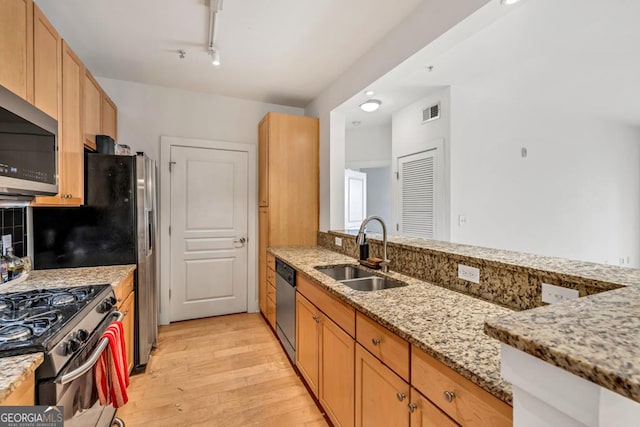 kitchen featuring light stone countertops, light wood-style flooring, visible vents, a sink, and appliances with stainless steel finishes