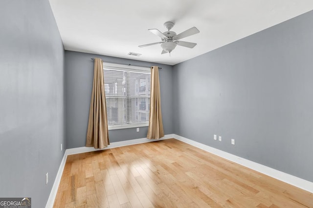 unfurnished room with baseboards, light wood-type flooring, visible vents, and a ceiling fan